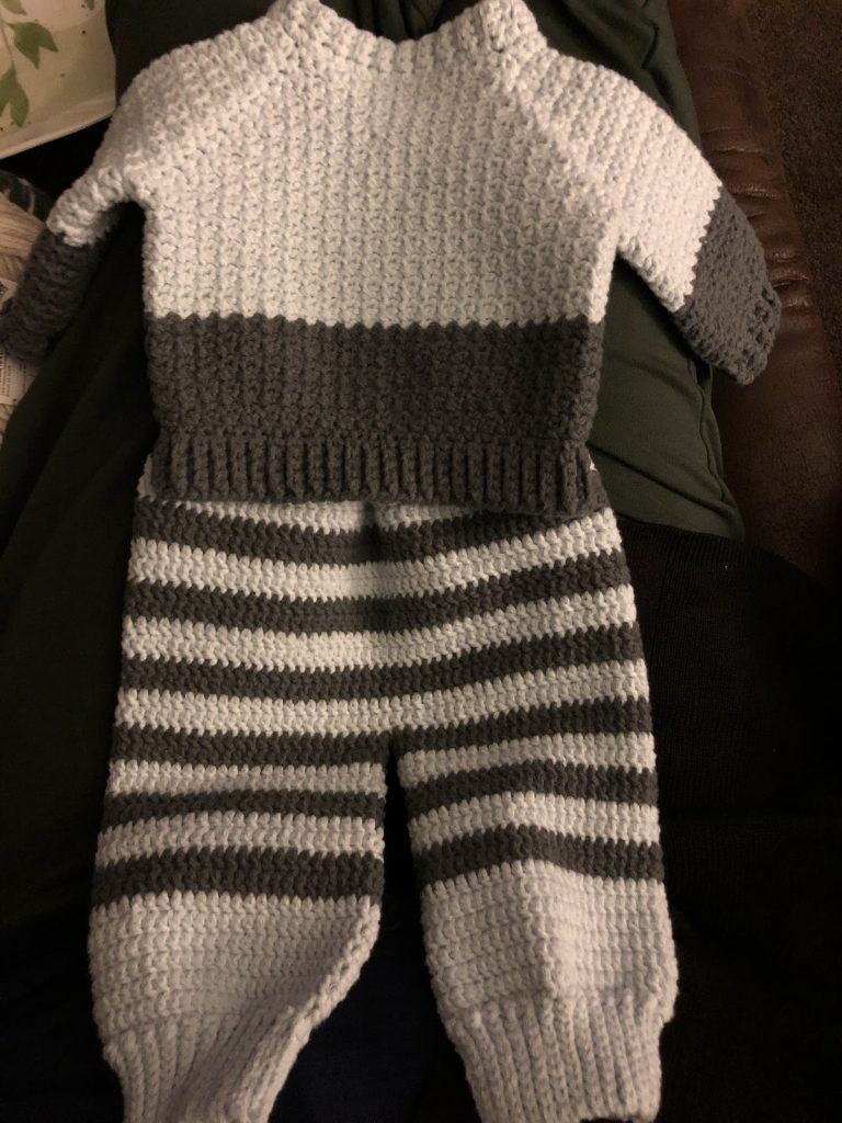 Example of a hand-knit sweater and trouser set for an infant.